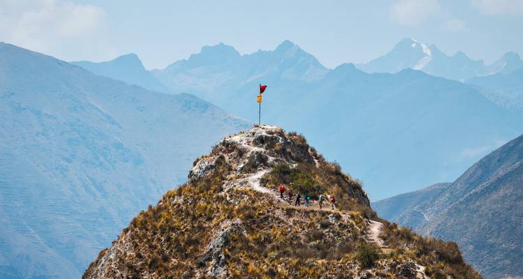 Hikers on a mountain trail with a scenic backdrop.