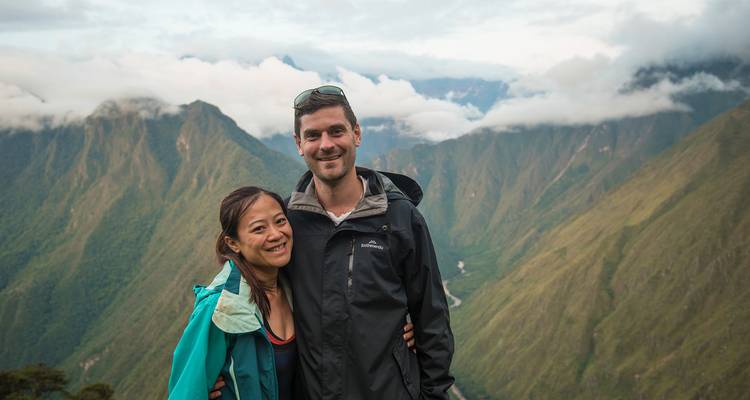 A couple posing with a mountainous background.