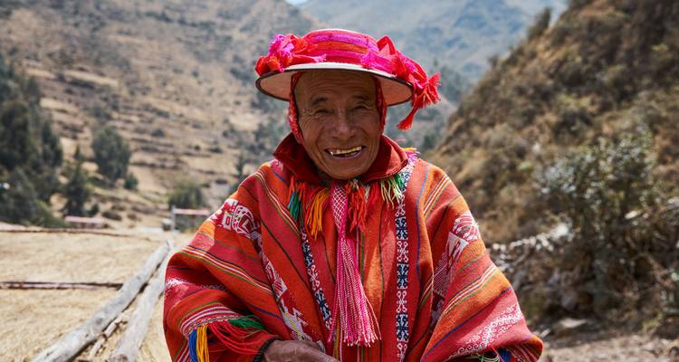Local person in traditional colorful attire against a mountainous backdrop.