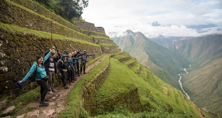 A group of hikers on a scenic trail with terraced ruins.