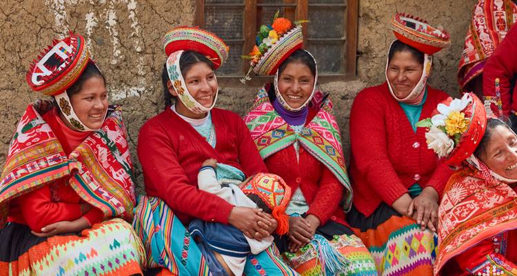 Group of women in traditional attire sitting together, smiling.