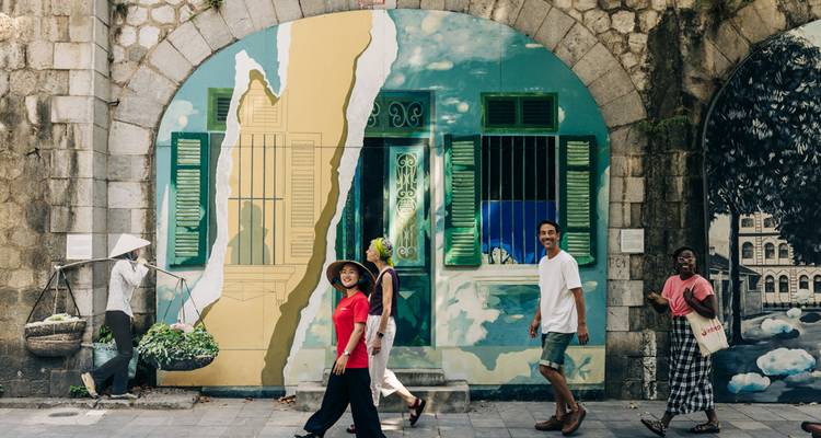 People walking past a mural in an urban area.