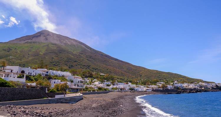 Coastal village with a view of a volcanic mountain.