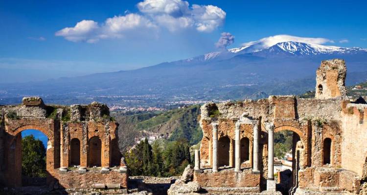 Les ruines de l'Ancien Théâtre de Taormine encadrent l'Etna fumant à travers un paysage sicilien lumineux.