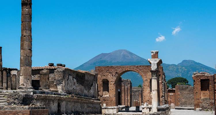 Oude ruïnes van Pompeïi met de Mount Vesuvius op de achtergrond onder een heldere hemel.