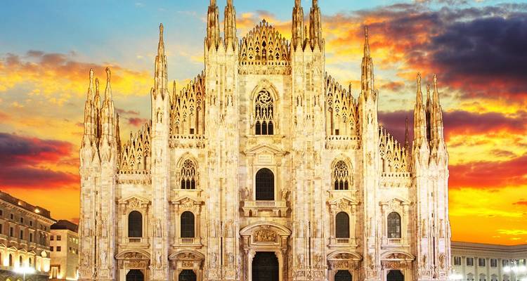 Fachada de mármol grandioso de la Catedral de Milán brillando al atardecer con un cielo de colores