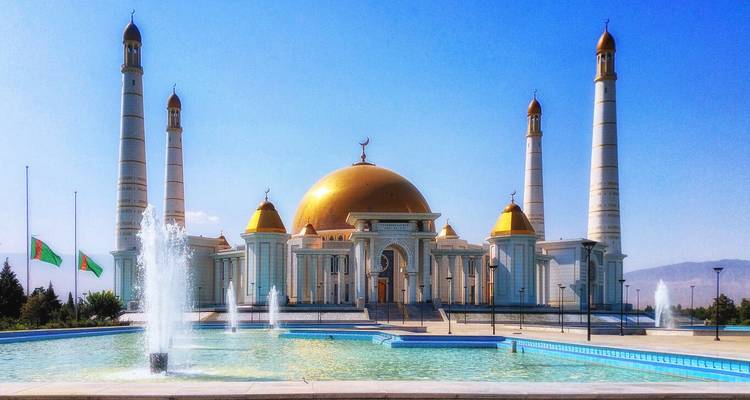 Eine große Moschee mit goldenen Kuppeln und weißen Minaretten unter einem sonnigen Himmel.