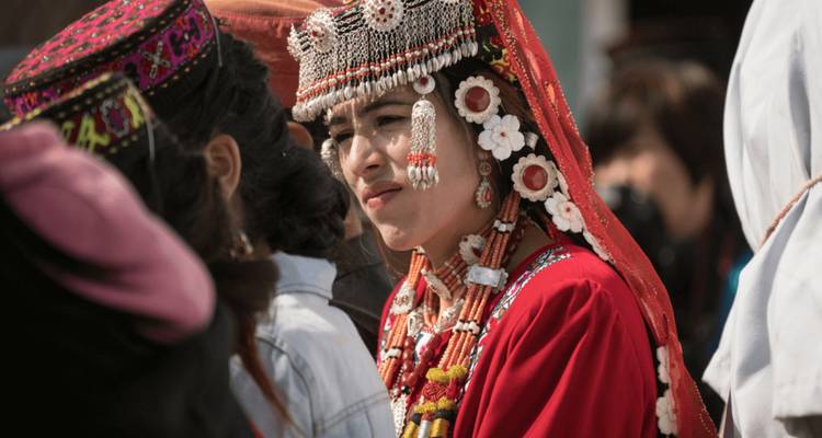 Eine Frau in traditioneller Kleidung, geschmückt mit Perlen und Stickereien.