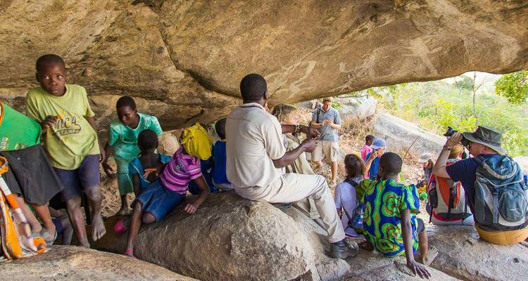Group of people exploring rock cave with carvings.