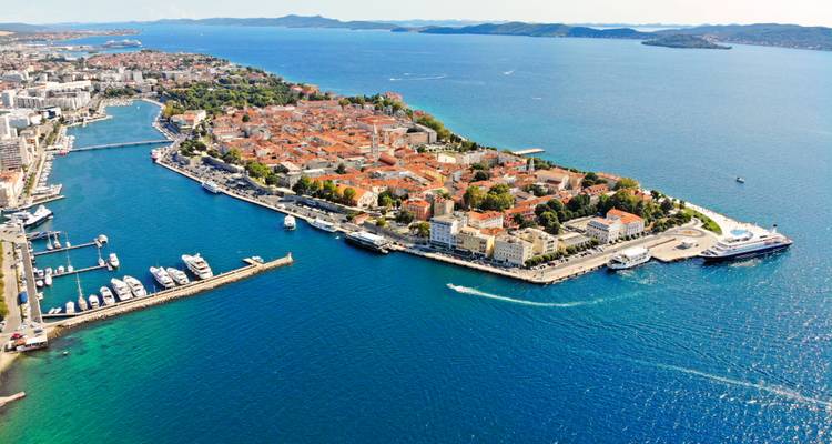 Panorama en plongée de la péninsule de Zadar entourée par les eaux bleu profond de la mer Adriatique avec des ports de plaisance et des toits en terre cuite.