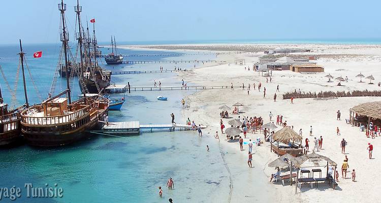Beach with ships and people enjoying the water with watermark.