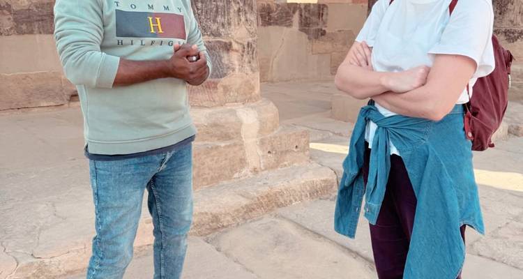 Deux personnes debout en train de converser dans un site historique extérieur.