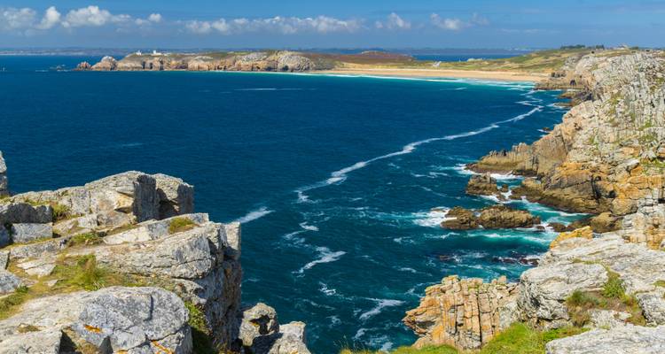 Des falaises rocheuses surplombant l'océan par une journée ensoleillée.
