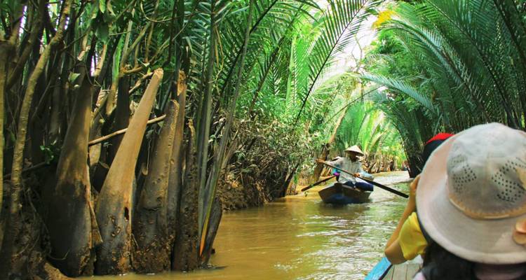 Des gens faisant du canoë à travers des voies navigables étroites bordées de palmiers.
