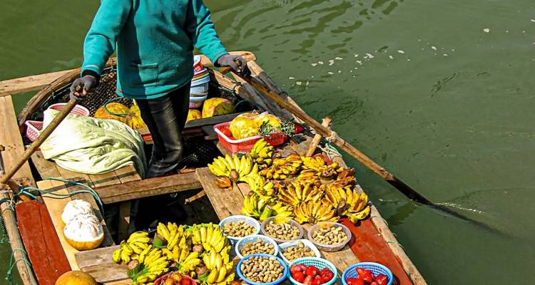 Vendeur de marché flottant vendant des fruits et légumes.