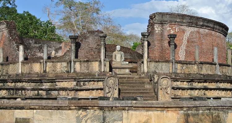 Ancient stone structure with staircases and a Buddha statue.