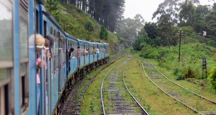 A blue train on a curving track with people looking out.