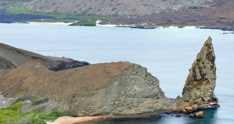 Gipfelförmige Felsformation am Meer mit einer entfernten Insel.
