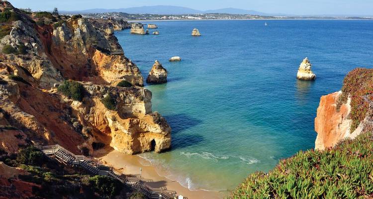 Coastal cliffs with clear blue sea and rocky formations.