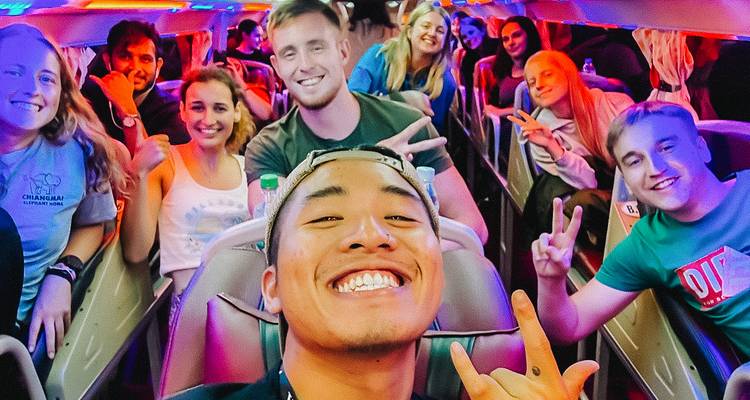 Passengers taking a selfie inside a vibrant night bus.