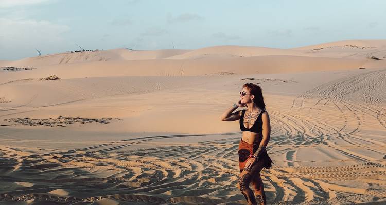 Person walking alone in expansive sandy dunes.