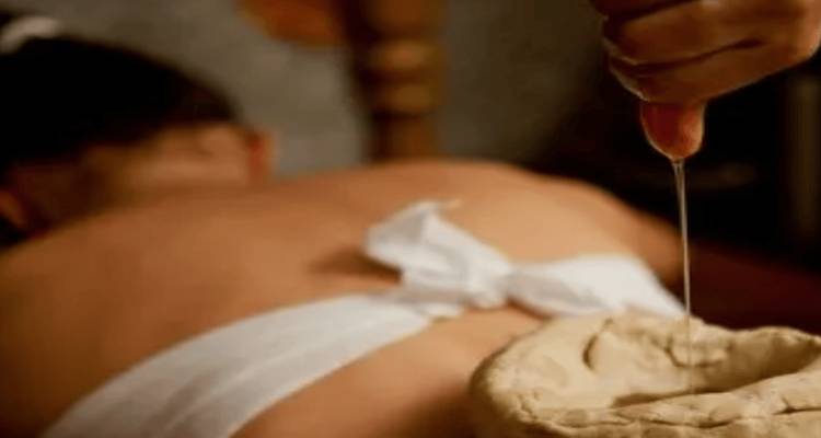 Blurry image of a person receiving a massage with oil being poured.