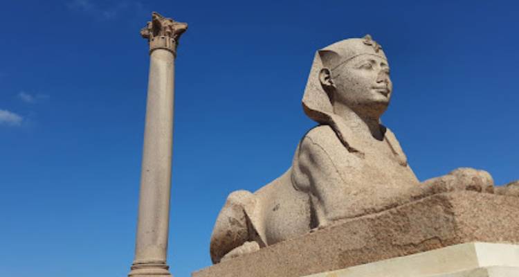 Statue de sphinx avec une colonne en arrière-plan.