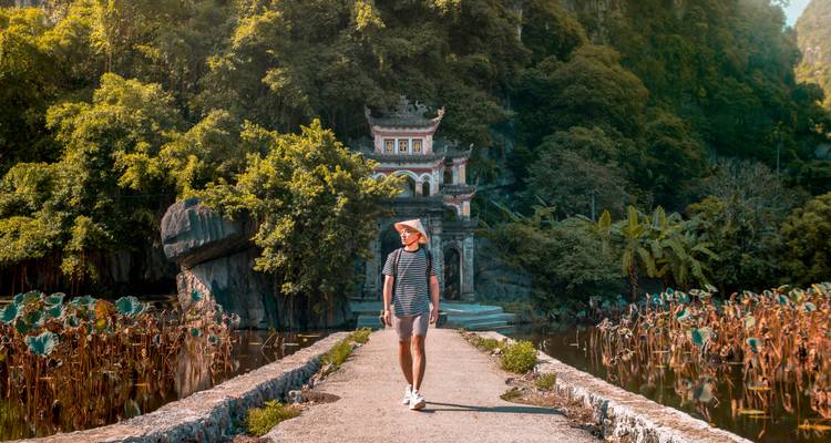 Individual walking towards a traditional gate with lotus flowers.