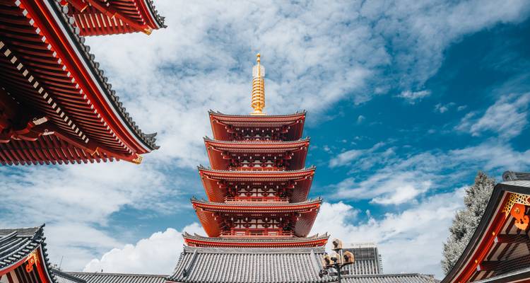 Red pagoda tower against a blue sky with decorative elements.