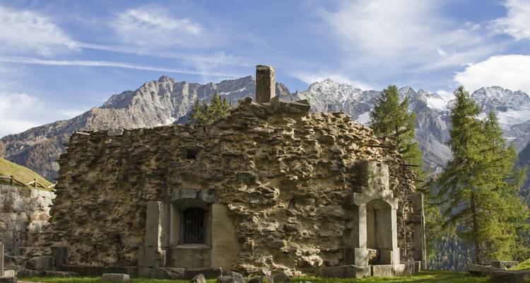 Alte Steinbefestigung mit Bergen im Hintergrund.