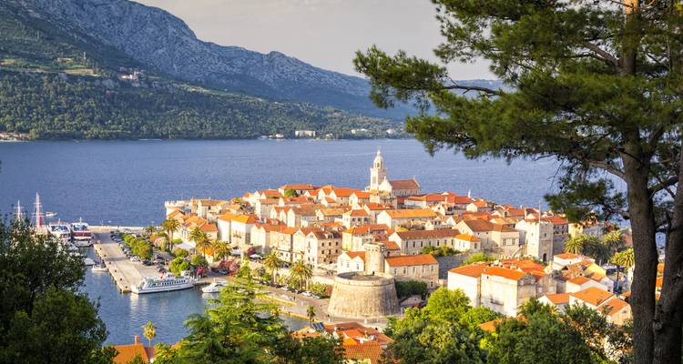 Vista aérea de un pintoresco pueblo costero con techos de tejas naranjas.