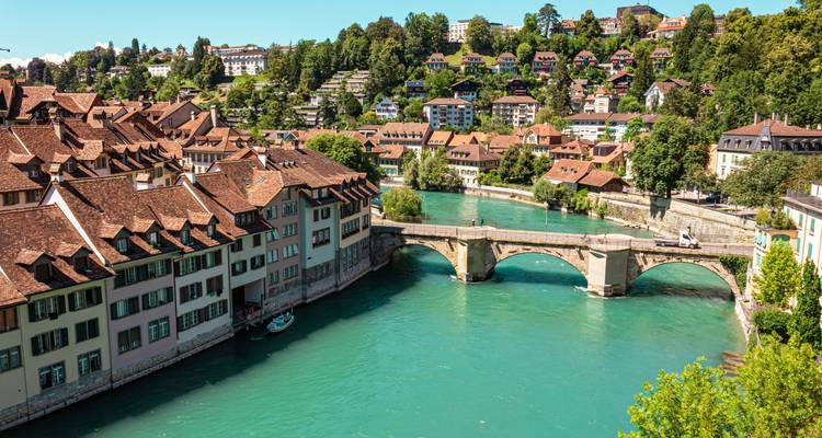 Aerial view of Bern’s old town with red-roofed houses lining the turquoise Aare River and a historic arched stone bridge.