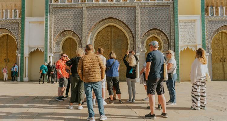 Tour group photographing the ornate golden gates of the Royal Palace in Fes.