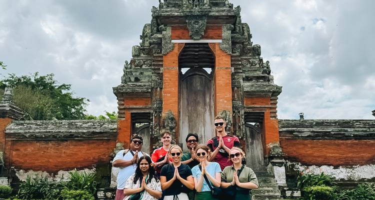 Group of tourists posing in front of a traditional Balinese temple.
