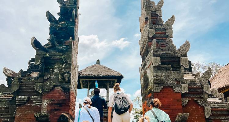 Tourists entering a Balinese temple with intricate stone carvings.