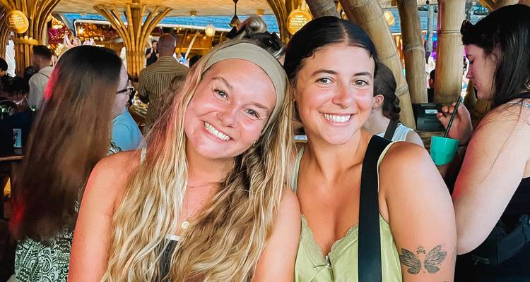 Two women smiling in a vibrant, bamboo-decorated setting.