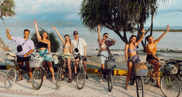 Group of people on bicycles posing with a coastal backdrop.