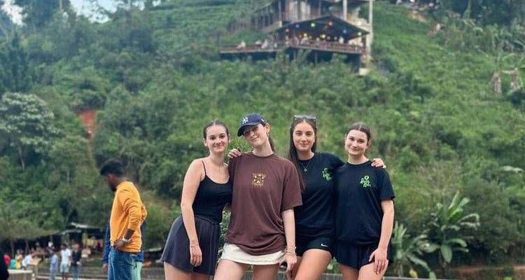 Groupe de personnes posant devant une colline verdoyante avec un bâtiment.