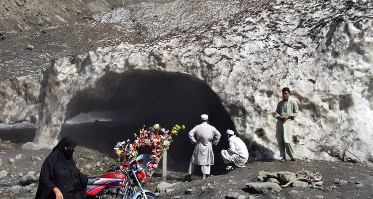 Des personnes visitant une grotte glacée avec un environnement enneigé.