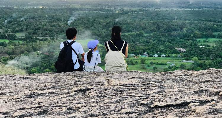 Group sitting and viewing a vast green landscape from a cliff.
