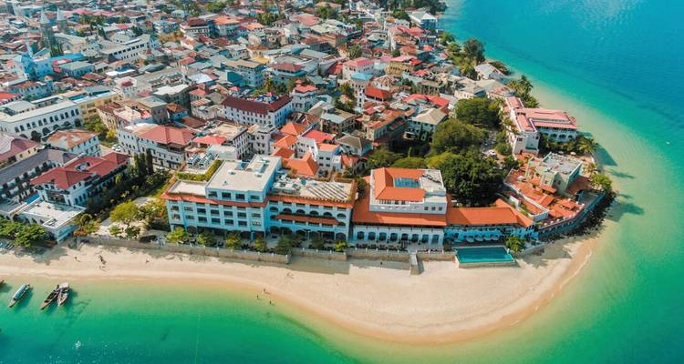 Aerial view of a coastal city with buildings and clear turquoise water.