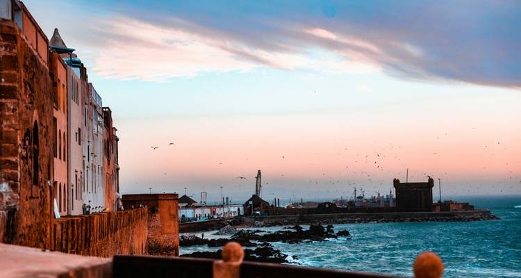 Vue sur le bord de mer avec bâtiments côtiers et ciel du soir.