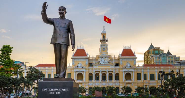 Statue of Ho Chi Minh in front of a colonial building.
