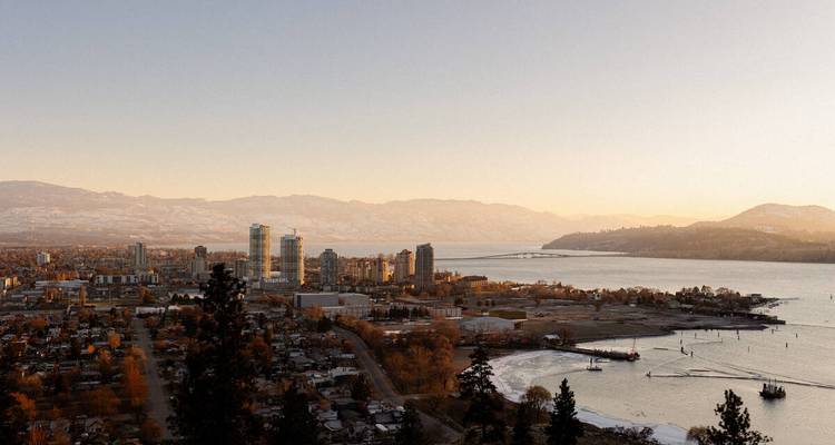 Paysage urbain au coucher du soleil avec des bâtiments et des montagnes près de l'eau.
