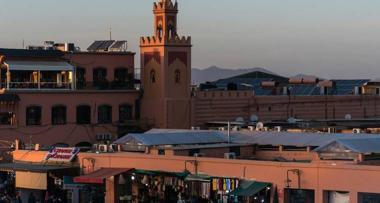 Une scène de marché animée avec une mosquée en arrière-plan au crépuscule.