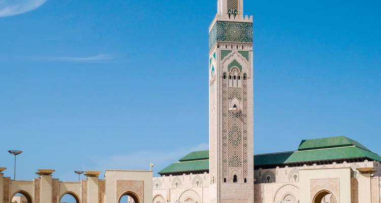 Grande mosquée avec un haut minaret sous un ciel bleu.