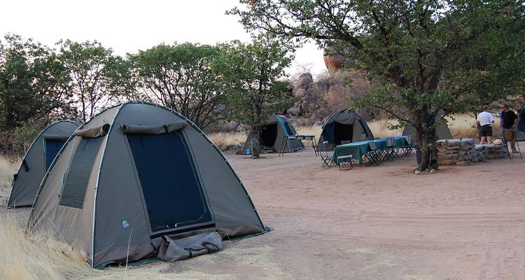 Campsite with tents in a desert area with people around.