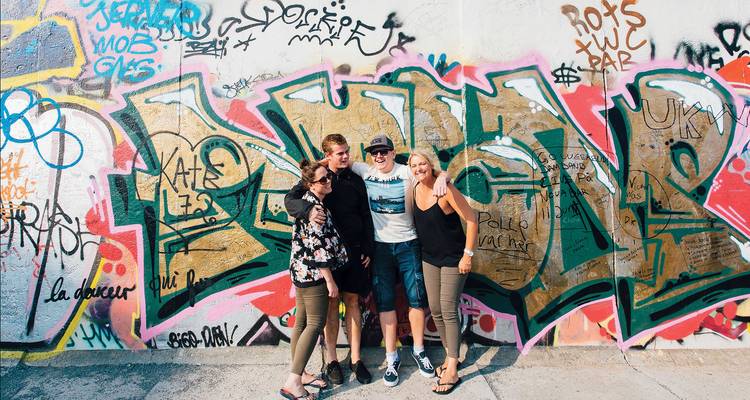 Group of people posing in front of a graffiti wall.