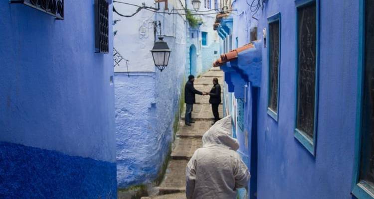 Ruelle bleue étroite avec des gens qui conversent et marchent.