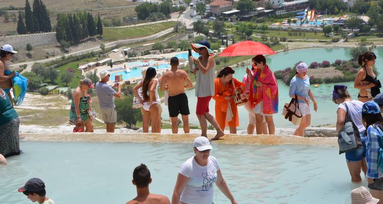 Tourists enjoying a natural thermal pool with views of the surroundings.